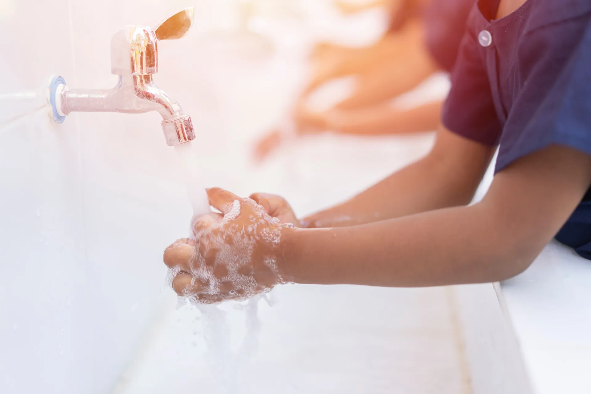 Criança lavando as mãos com sabão em uma pia, praticando uma higiene básica e essencial.