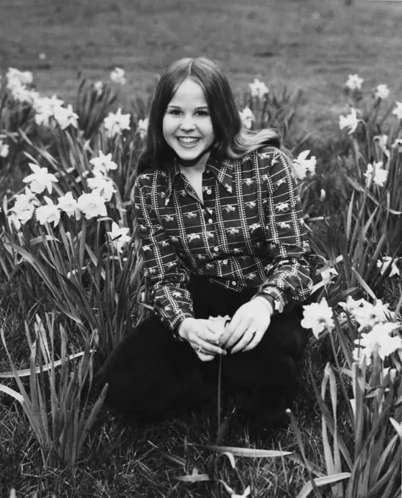 Linda Blair sorrindo, na época em que filmou 'O Exorcista', mostrando o contraste com sua personagem.