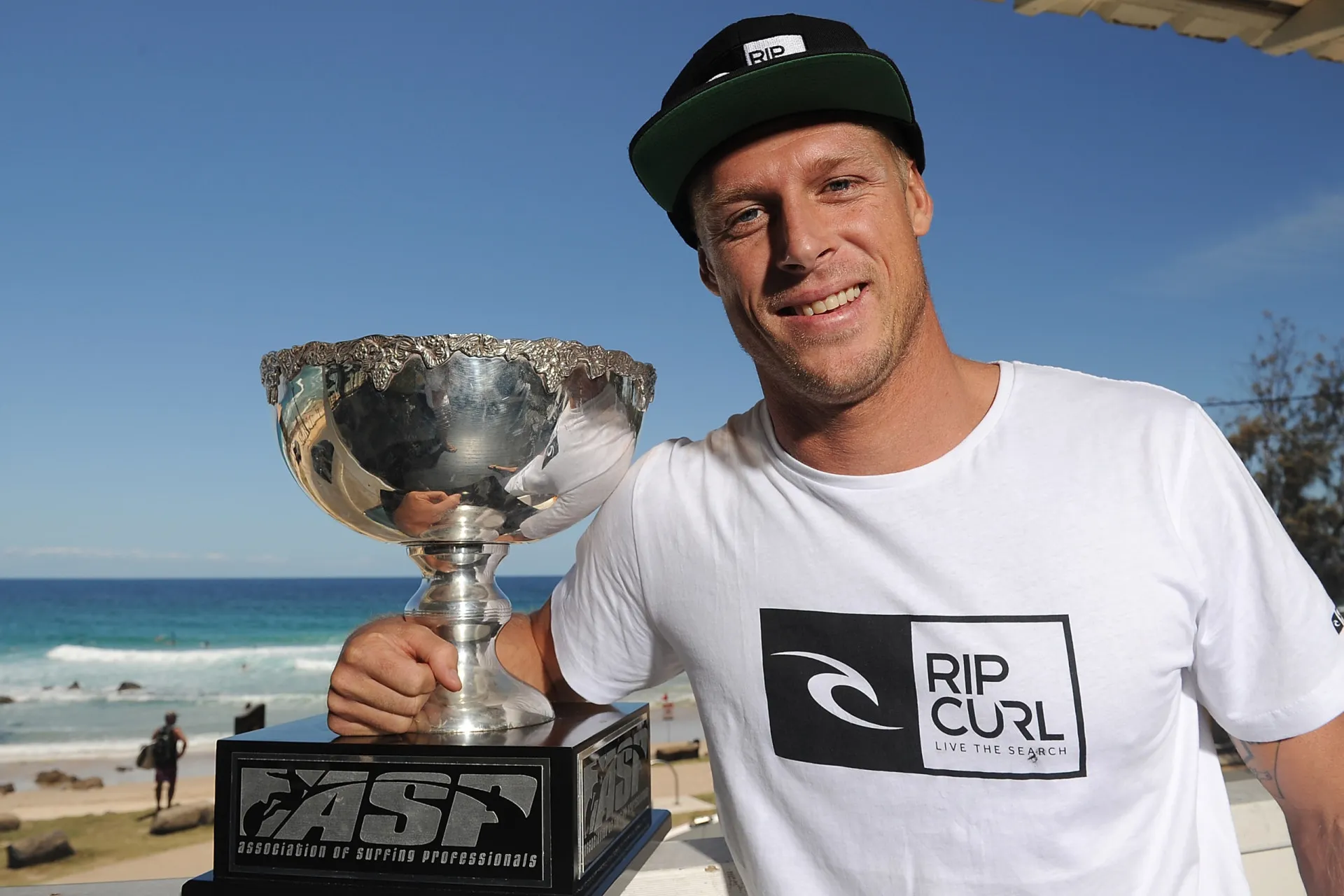 Mick Fanning sorrindo com sua prancha de surfe.