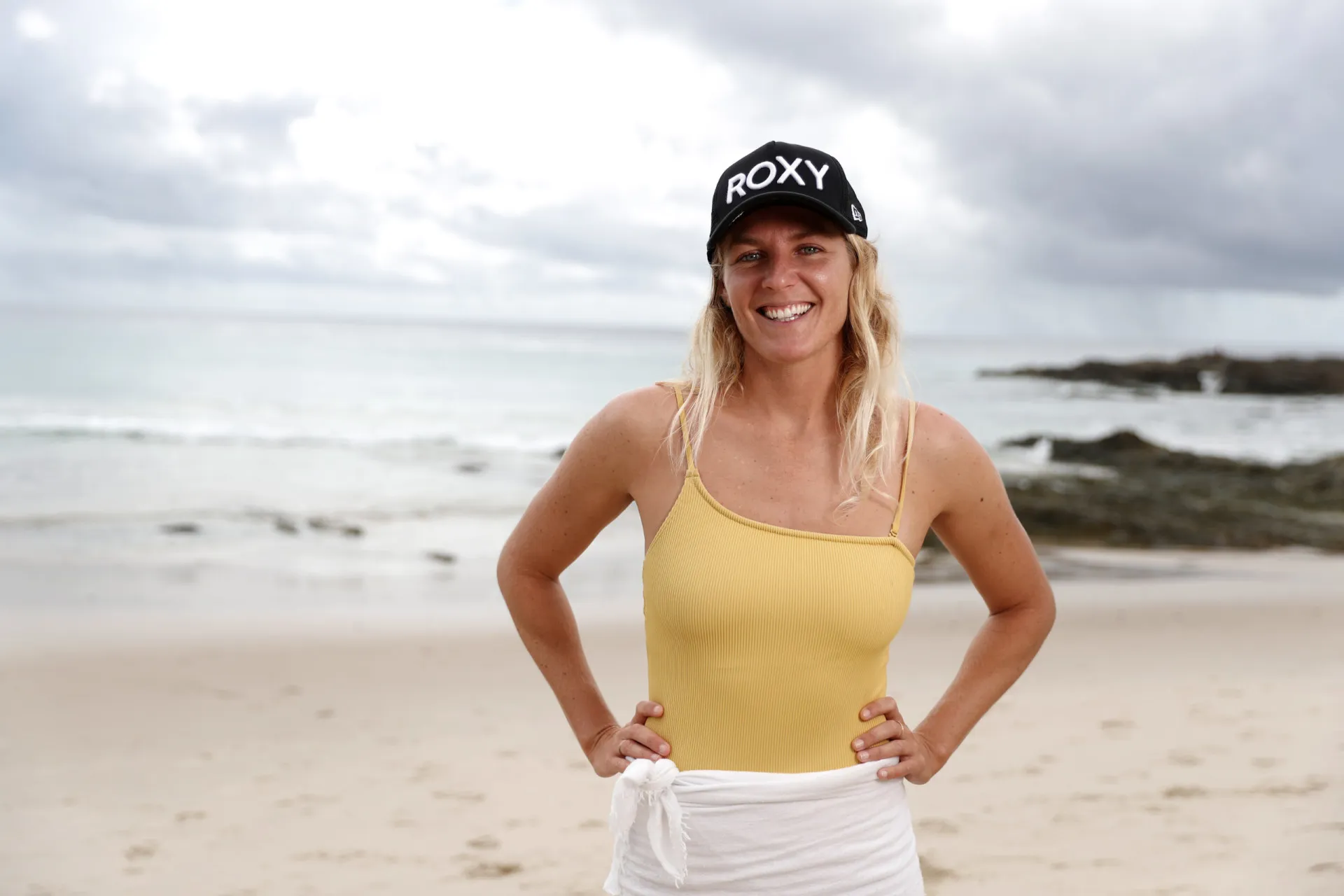 Stephanie Gilmore sorrindo, uma das maiores atletas do surfe feminino.