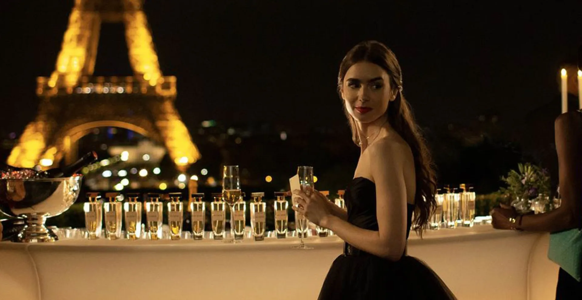 Lily Collins como Emily na série 'Emily in Paris', com a Torre Eiffel ao fundo.