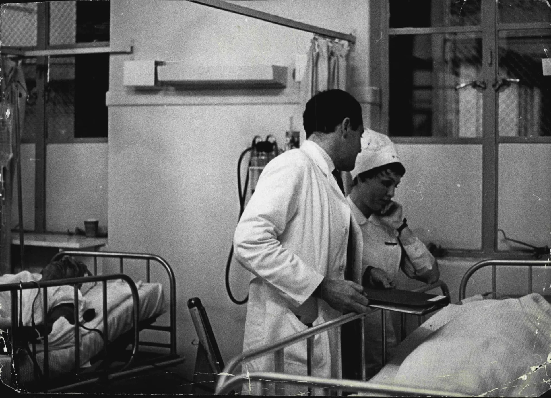 Uma mulher com rosto pálido e sem expressão em um corredor de hospital.