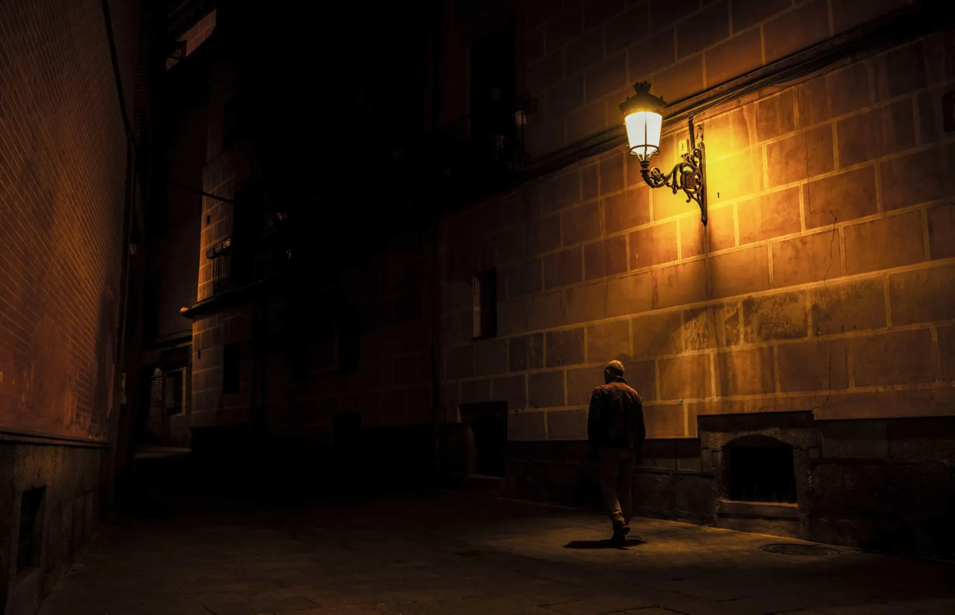 Silhueta de um homem em uma rua escura e vazia à noite.