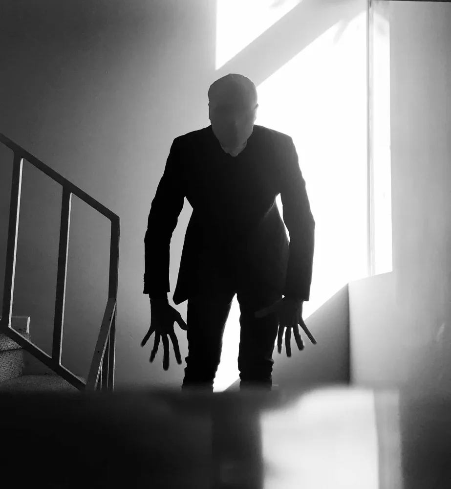 Slender Man usando seu terno escuro, com braços anormalmente longos.