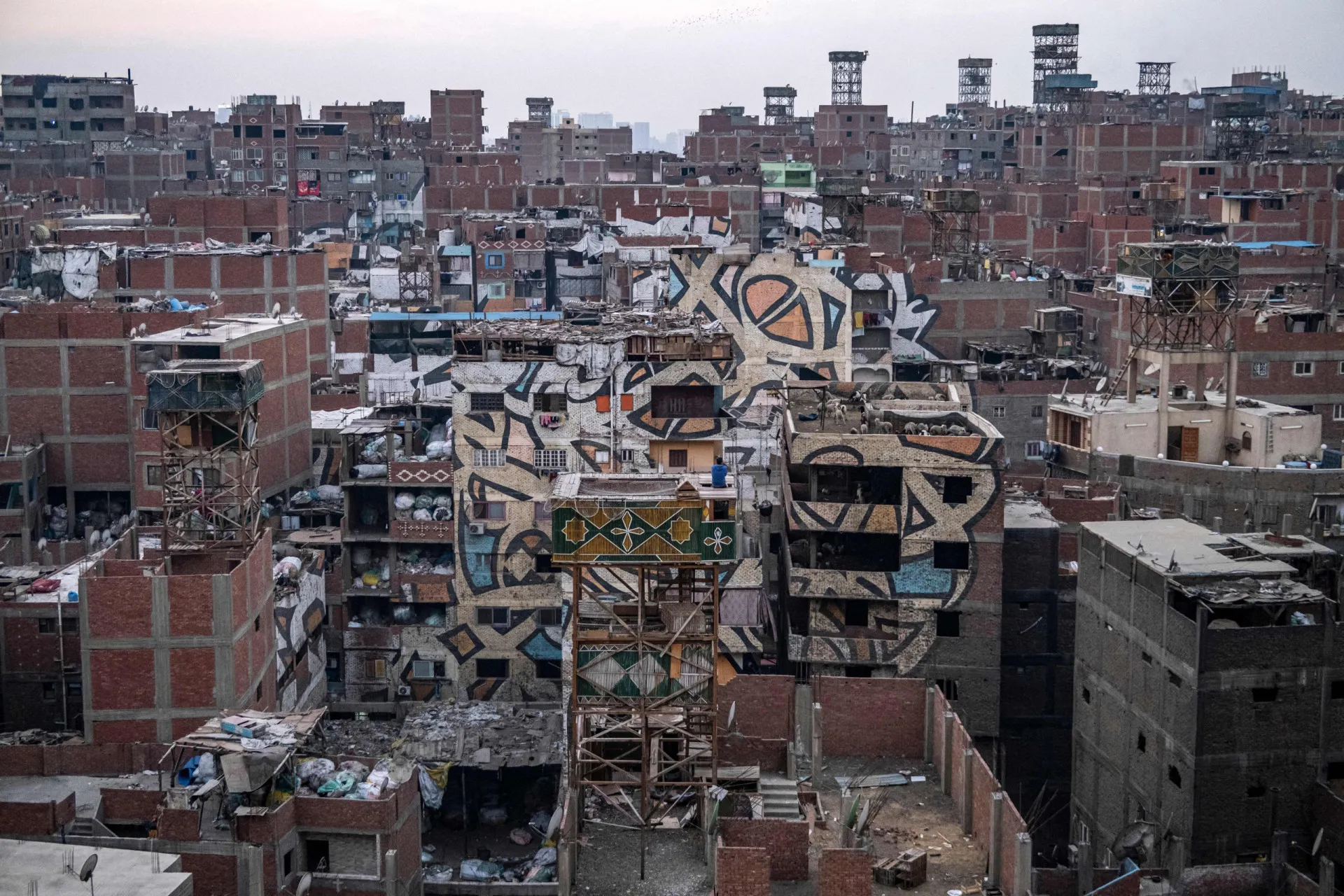 Homem trabalhando com uma grande quantidade de lixo reciclável na favela de Manshiyat Naser.