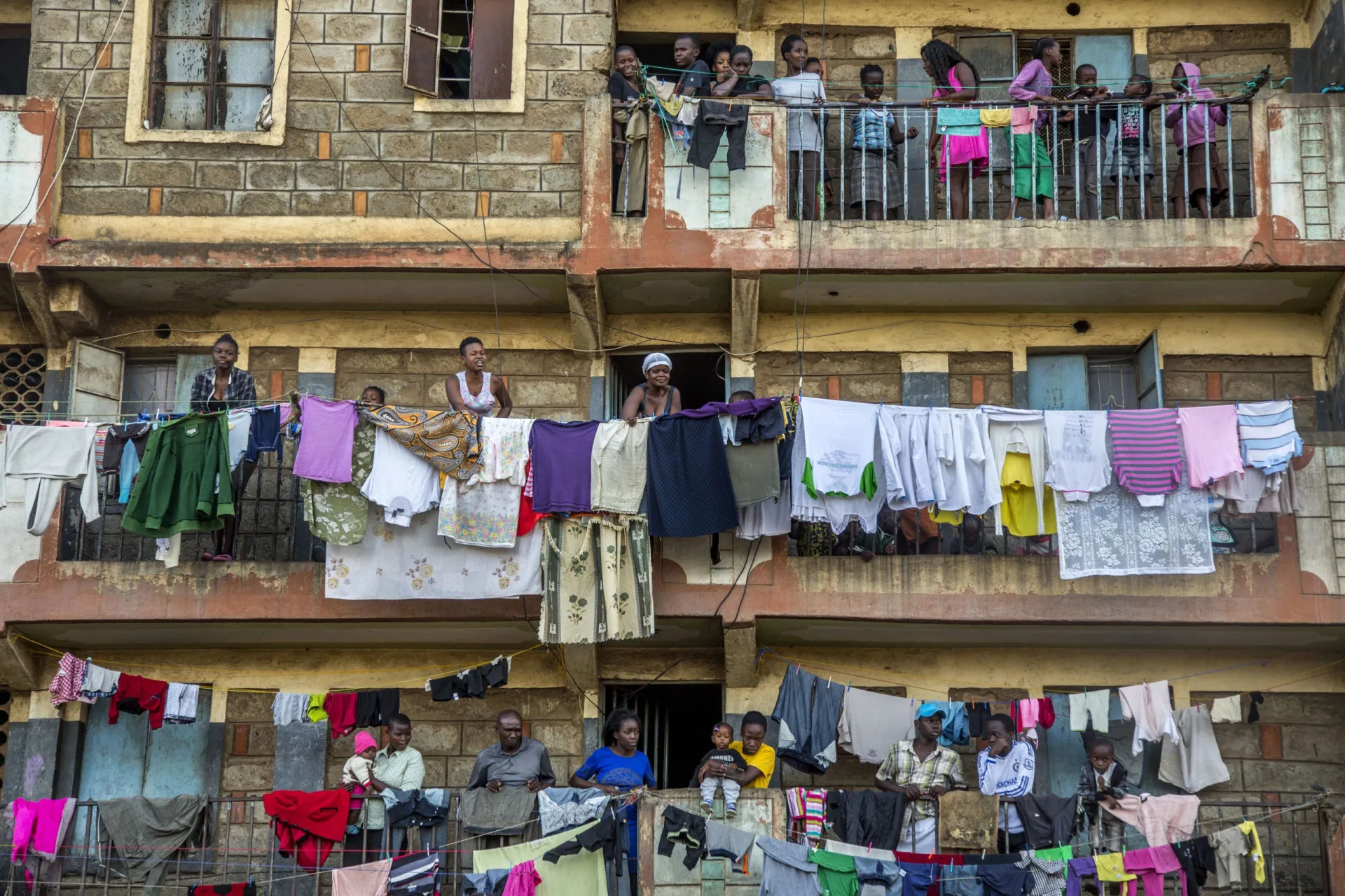 Crianças caminhando por um beco estreito e lamacento na favela de Mathare, no Quênia.