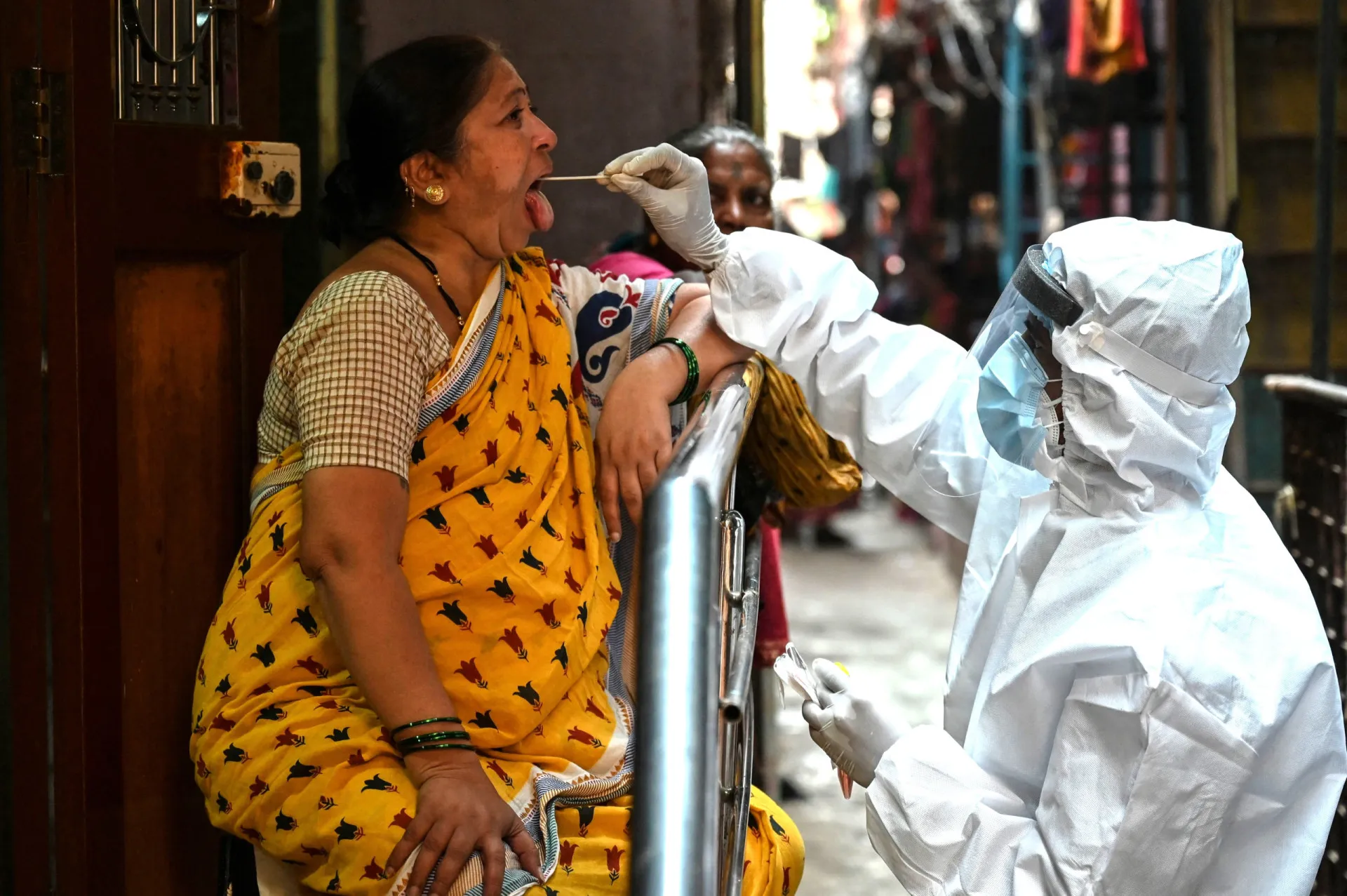 Rua estreita e lotada de Dharavi, com comércios e moradias lado a lado.