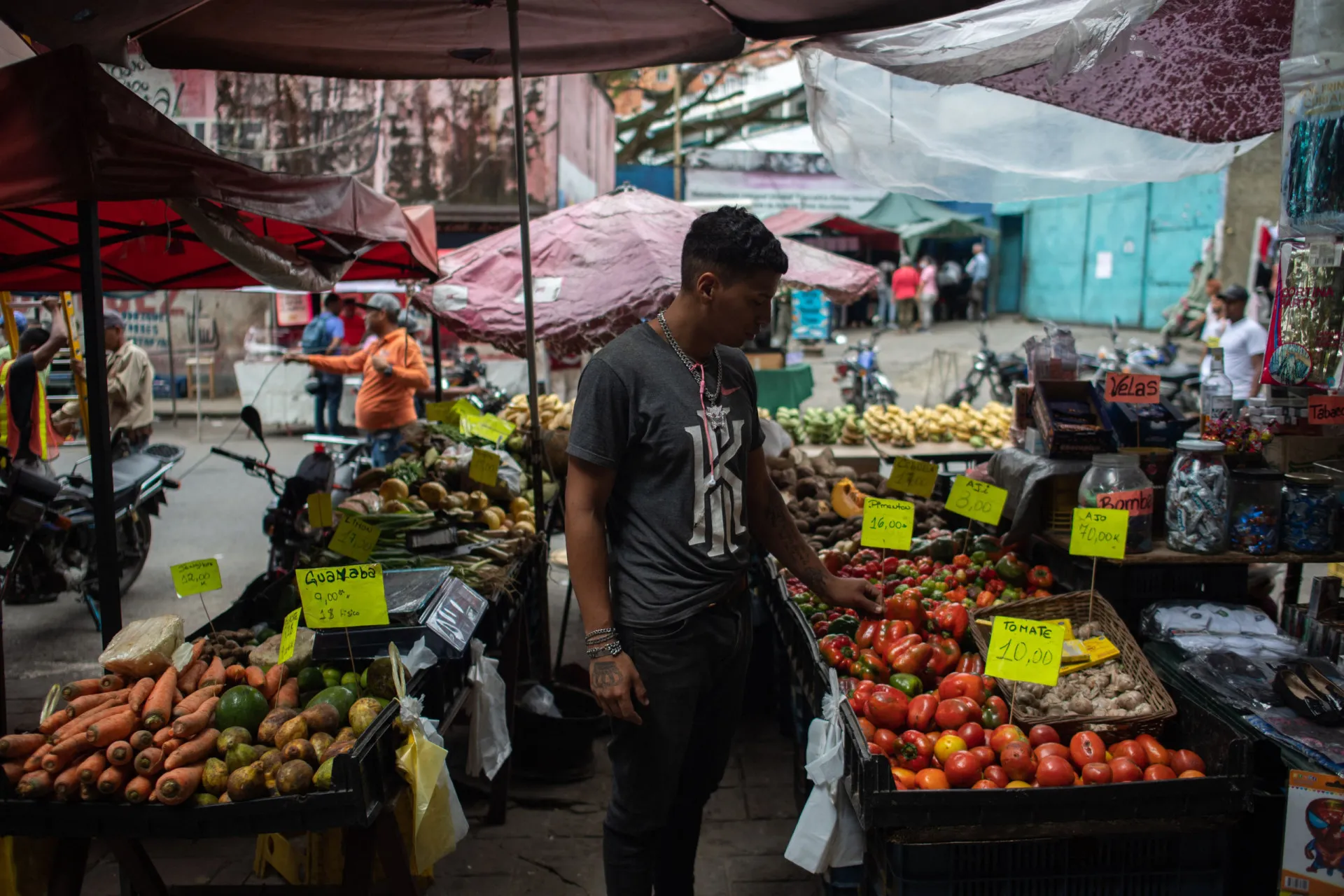 Mercado de rua em Petare, com uma multidão de pessoas comprando e vendendo produtos.