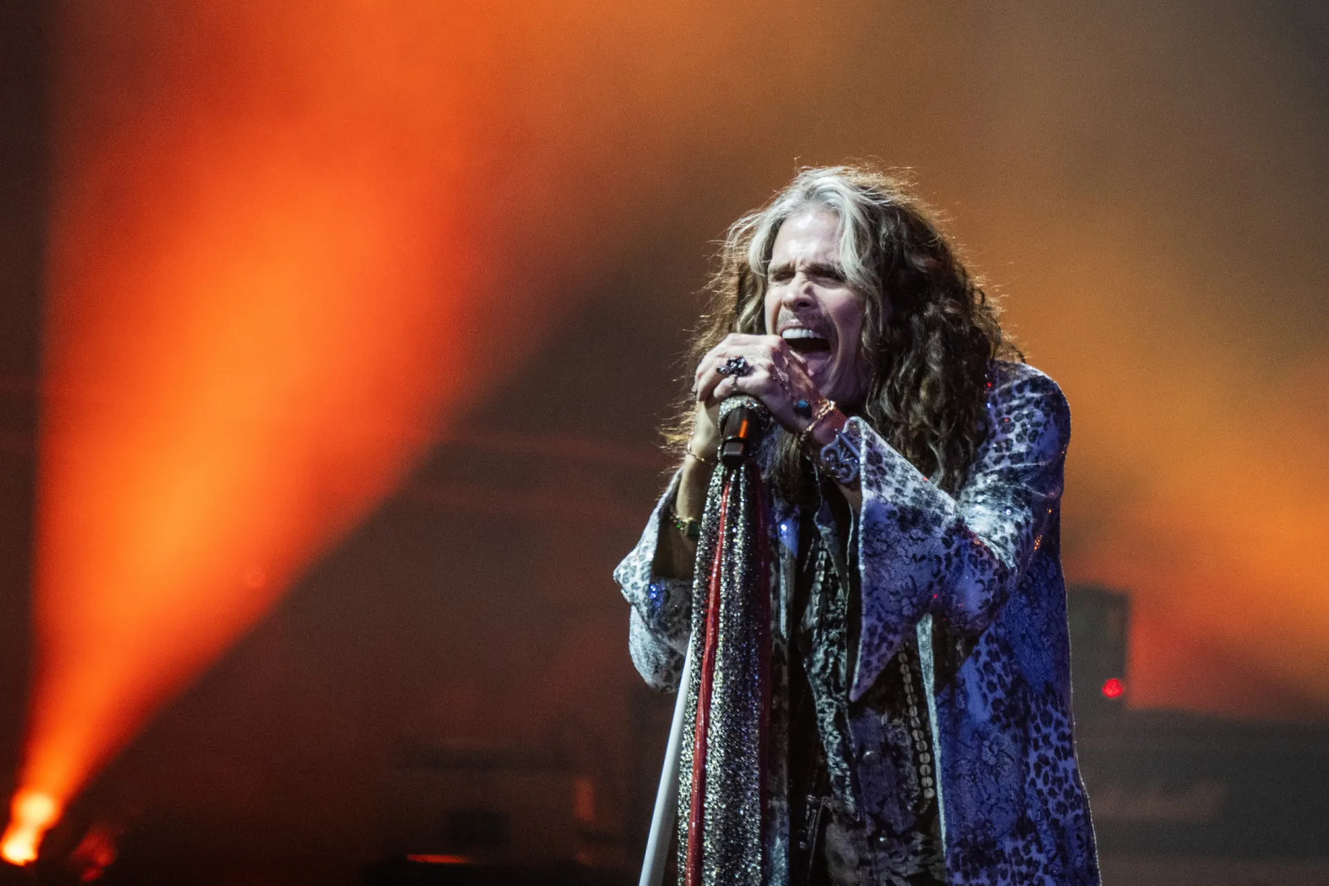 Steven Tyler, do Aerosmith, cantando com sua energia característica em um show.