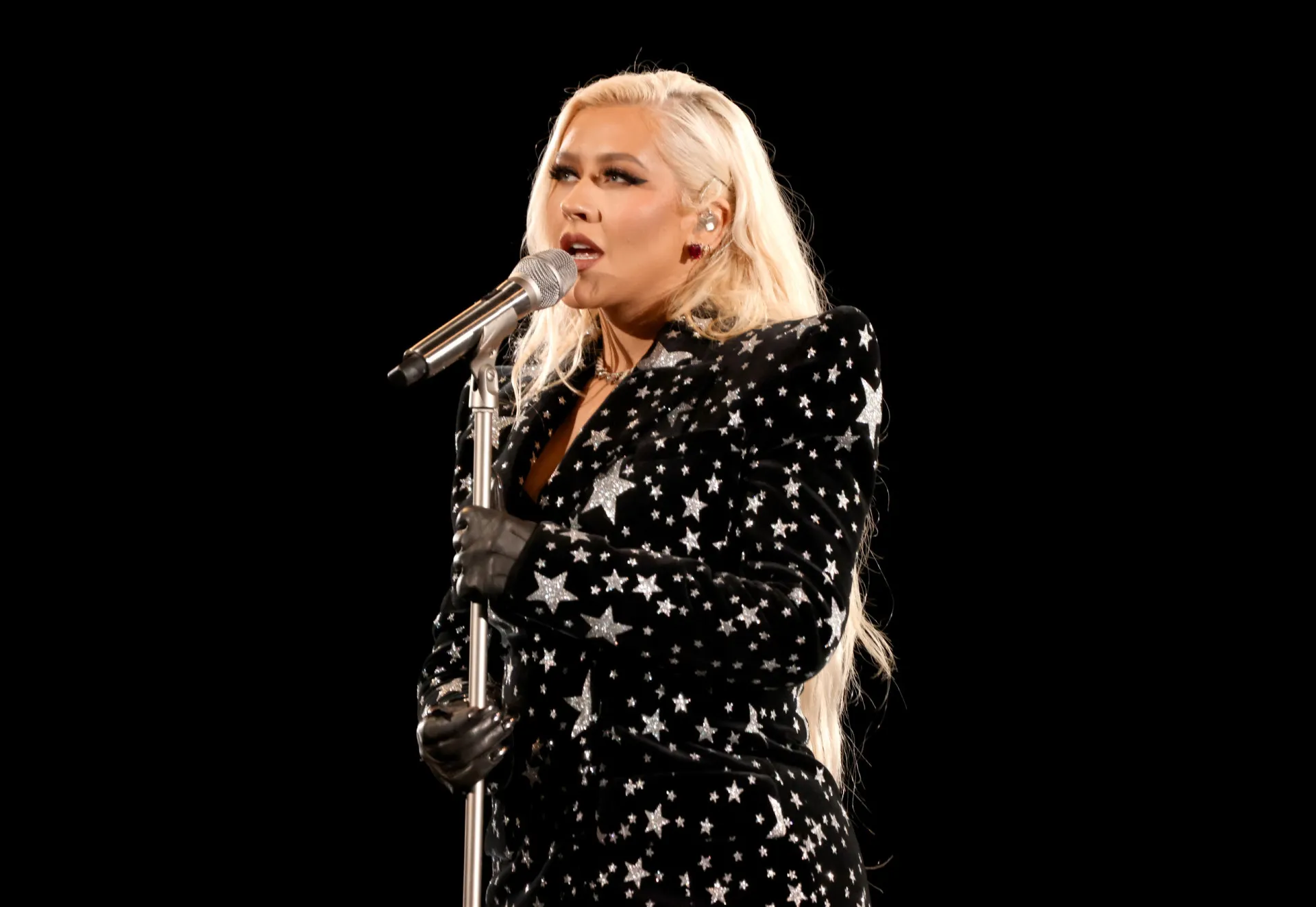 Christina Aguilera com um visual retrô, cantando com expressão de dor e paixão.