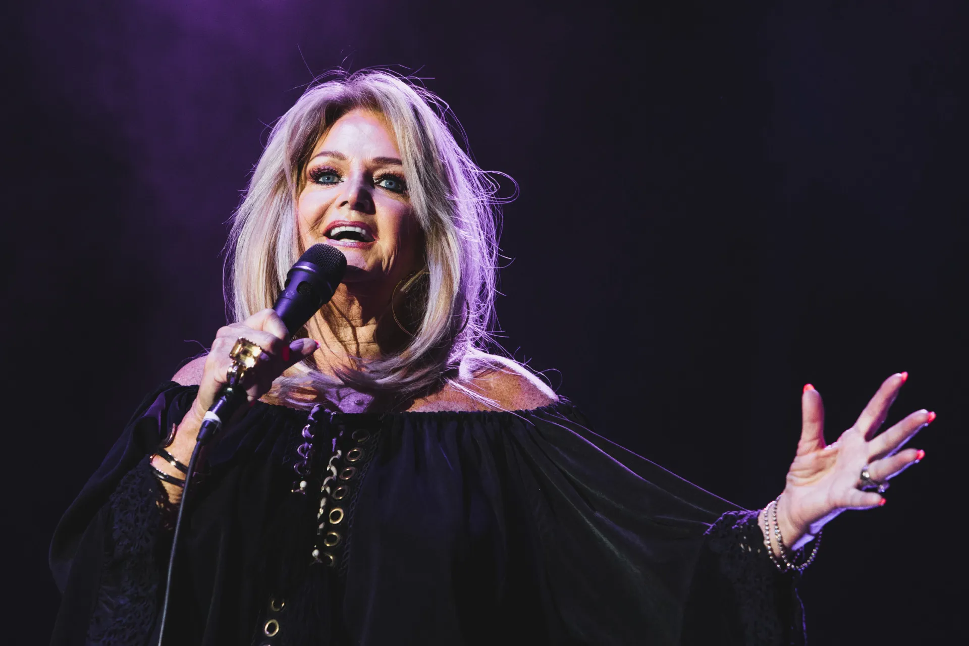 Bonnie Tyler com seu cabelo volumoso dos anos 80, cantando com uma expressão poderosa.