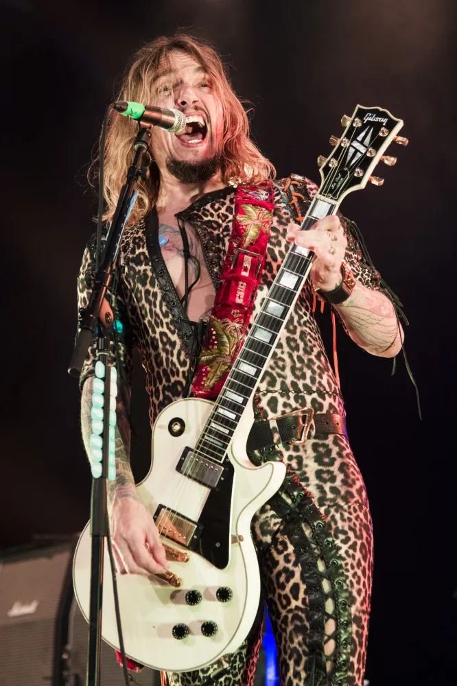 Justin Hawkins, do The Darkness, com seu macacão característico, tocando guitarra e cantando.