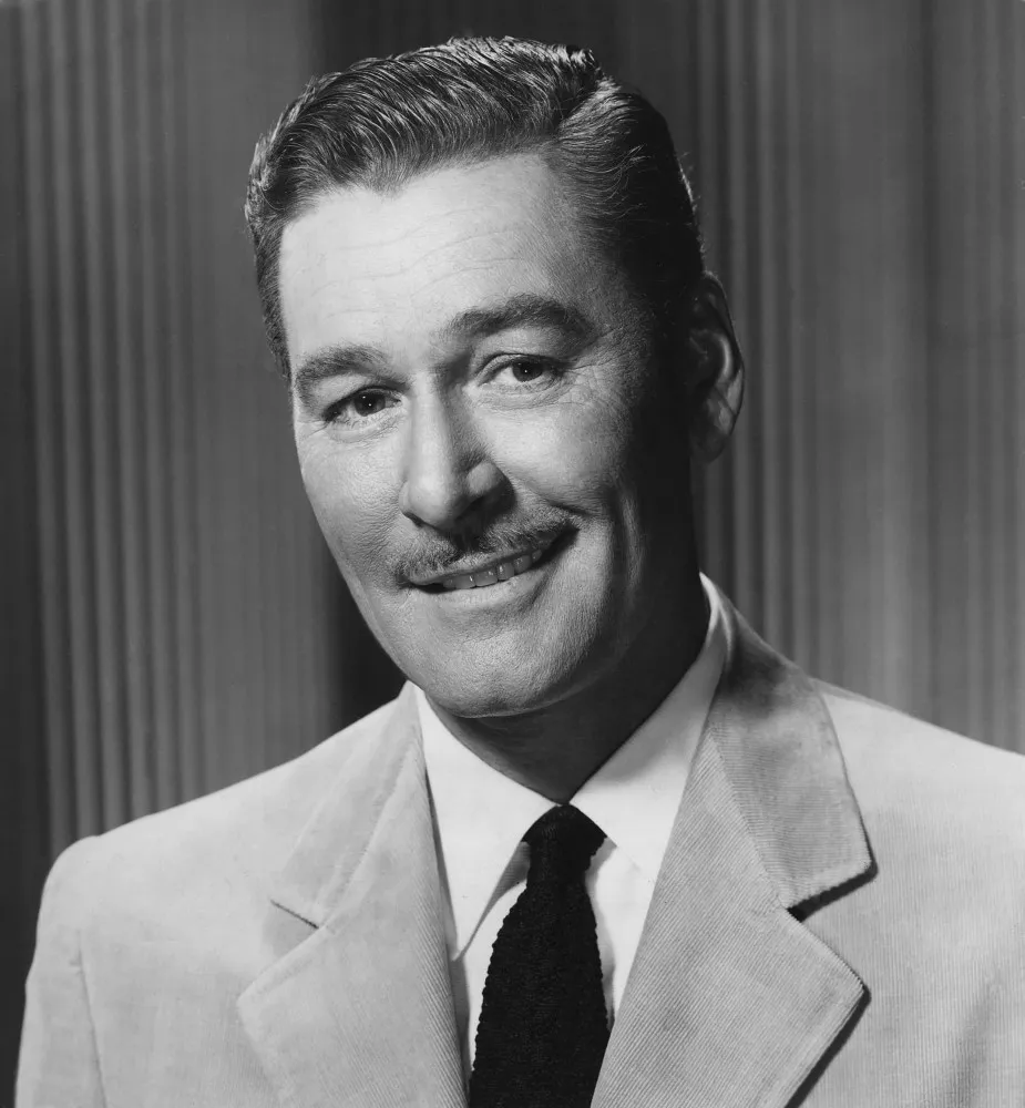 O ator Errol Flynn, famoso por seus papéis de aventureiro e galã, com um sorriso charmoso.