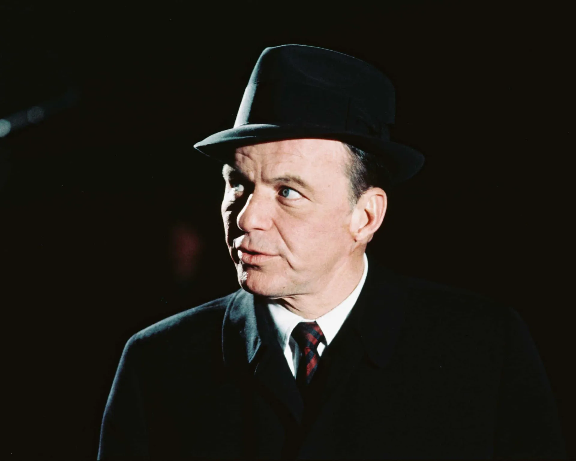 Frank Sinatra, o lendário cantor conhecido como 'A Voz', segurando um microfone.