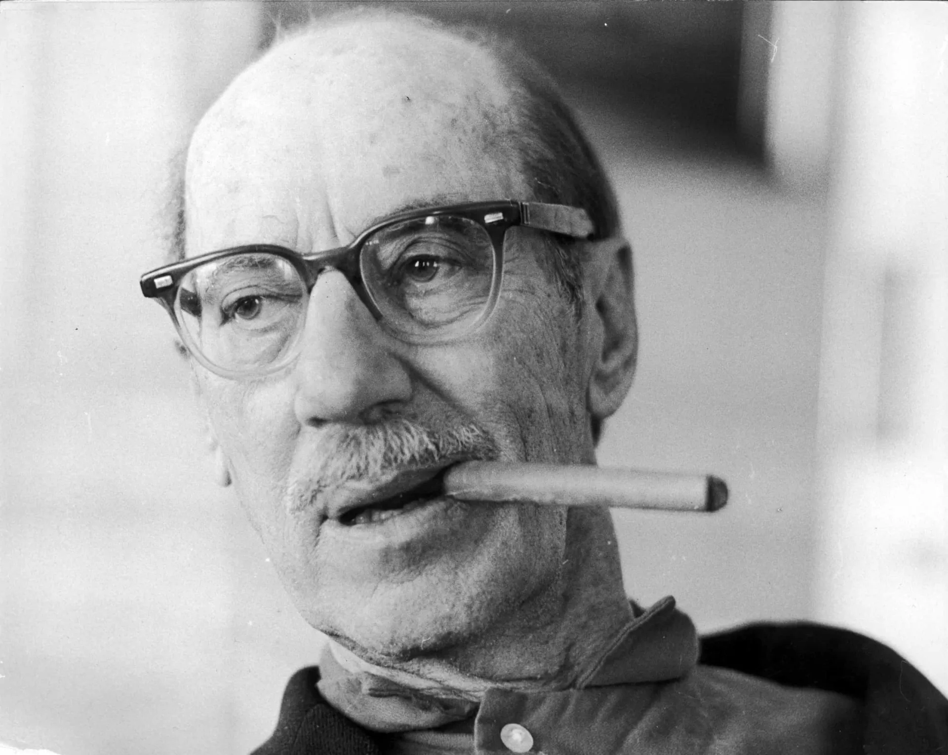 O comediante Groucho Marx com seus óculos, bigode e charuto icônicos, em uma pose engraçada.