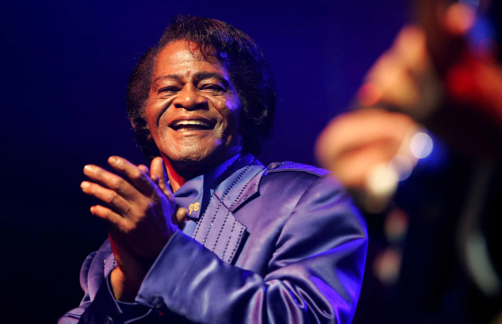 James Brown, o 'Padrinho do Soul', suando e cantando com toda a sua energia no palco.