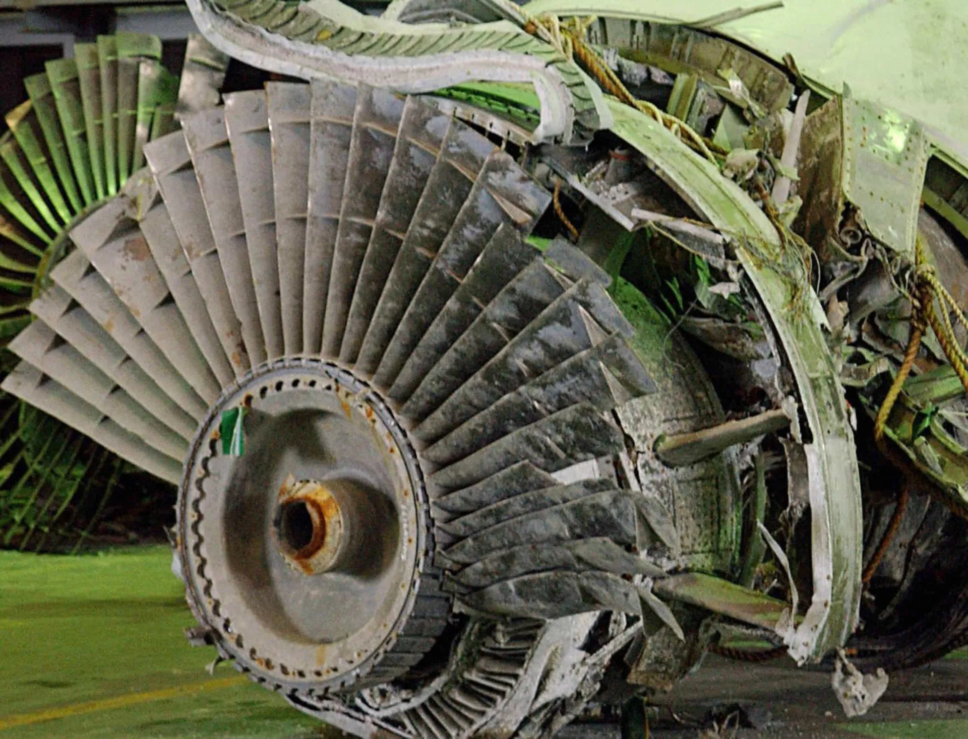Um motor de avião recuperado do mar, sendo exibido em um hangar para investigação.