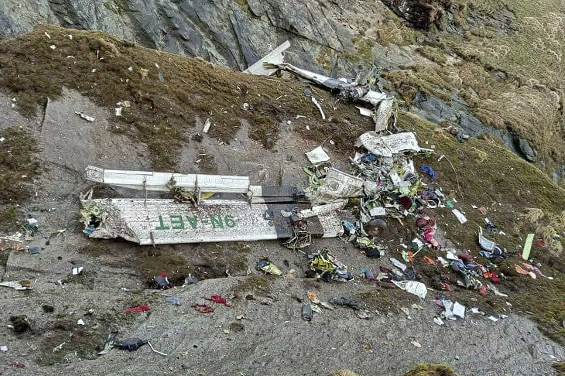 Destroços de um avião pequeno espalhados na encosta de uma montanha rochosa.