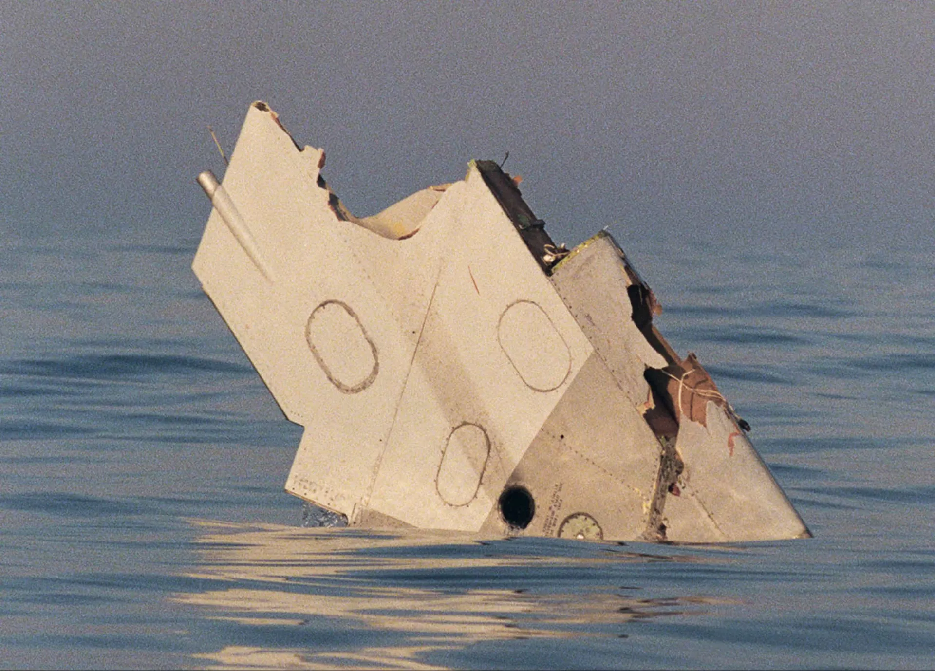 Parte da asa de um Boeing 747 flutuando no oceano após uma explosão.