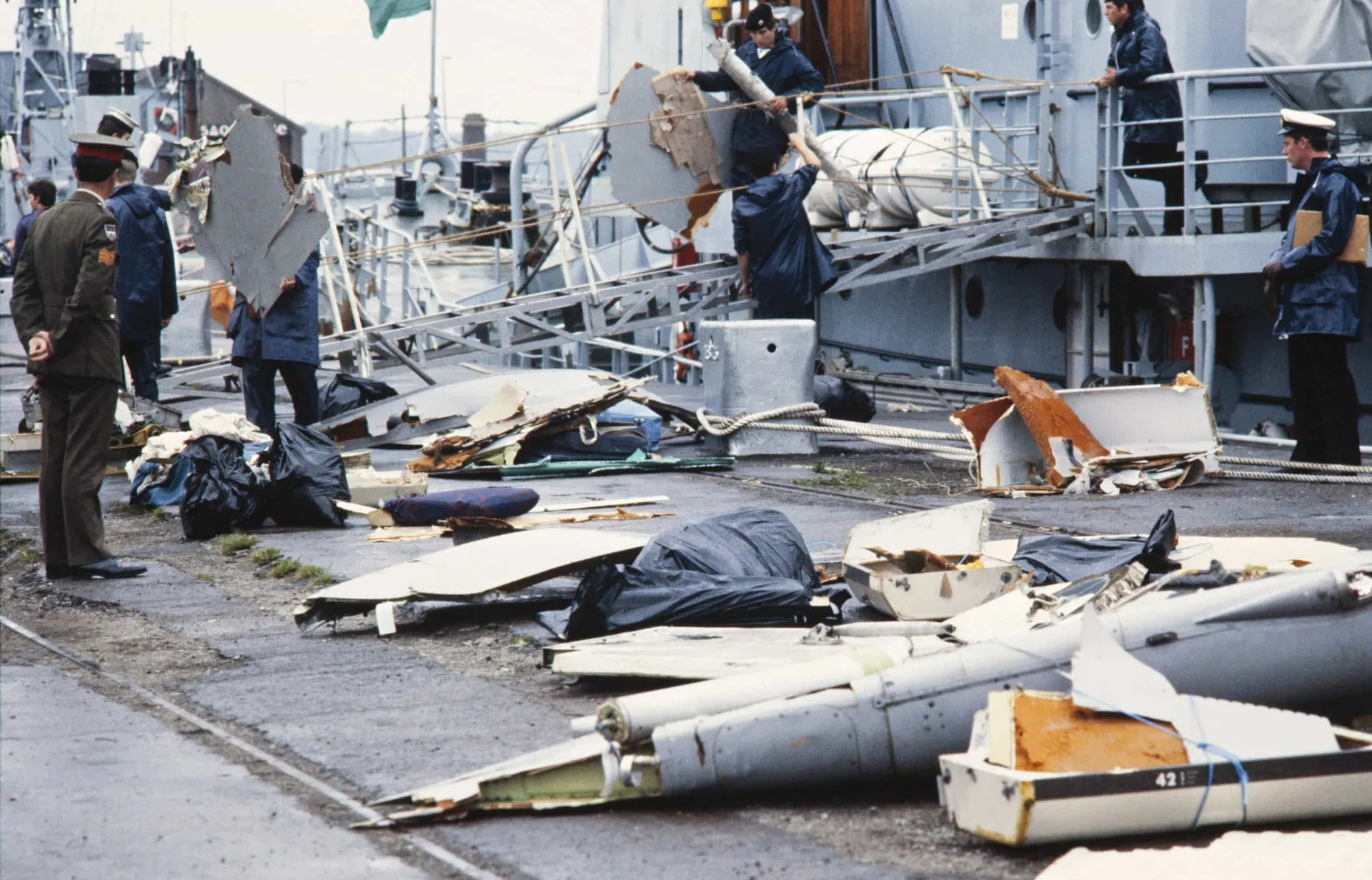 Tripulantes de um navio naval recolhendo destroços de avião do oceano.