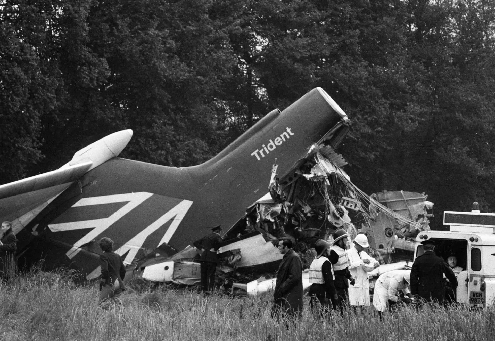 Destroços de um avião em um campo, com a cauda da aeronave intacta e visível.