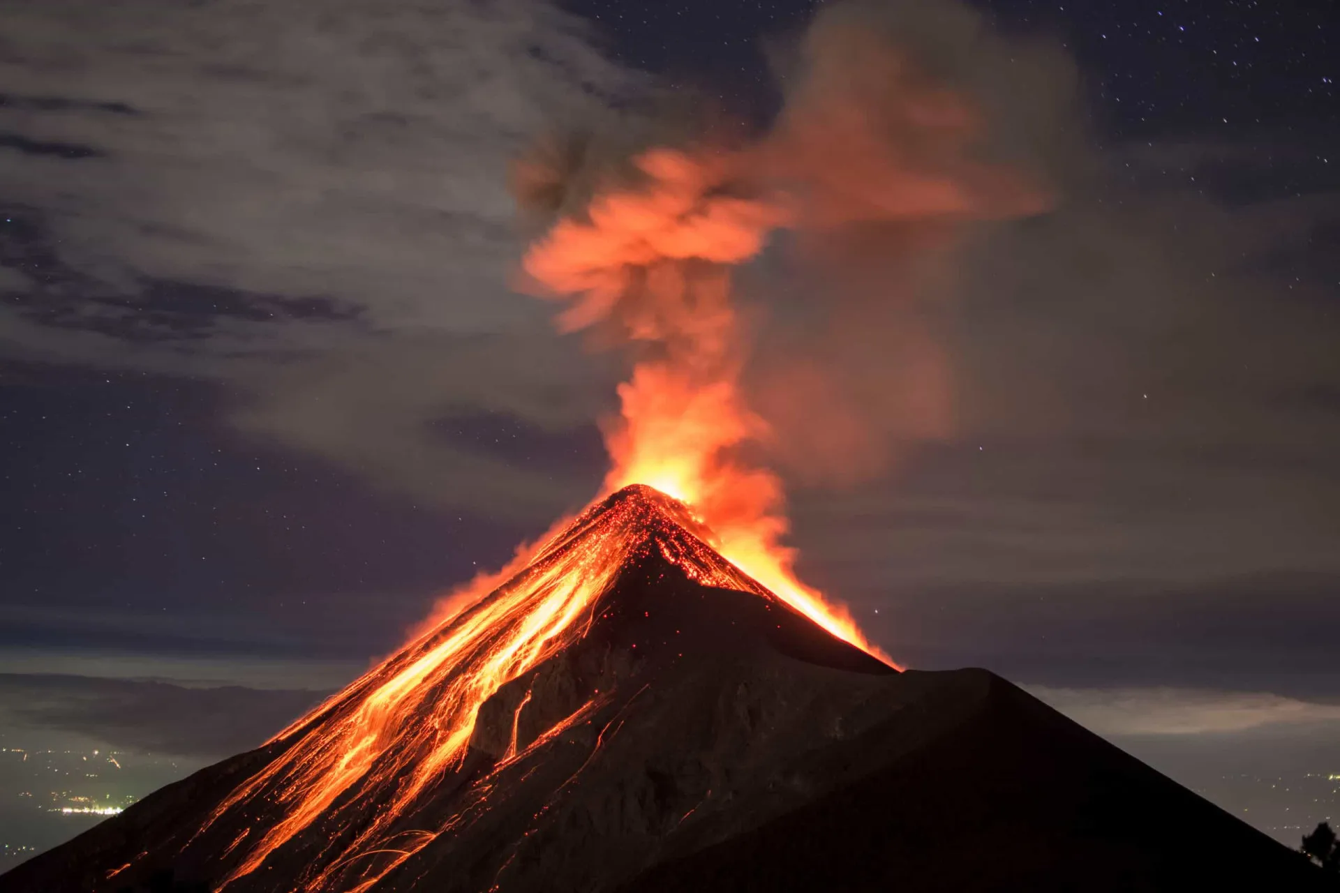 Imagem de um vulcão em erupção expelindo cinzas e fumaça para o céu.
