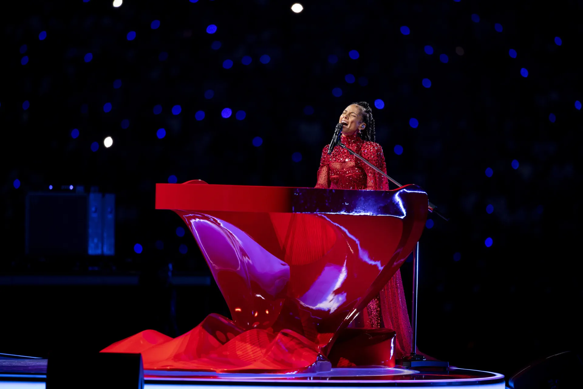 Alicia Keys sentada ao piano, sorrindo durante uma performance.