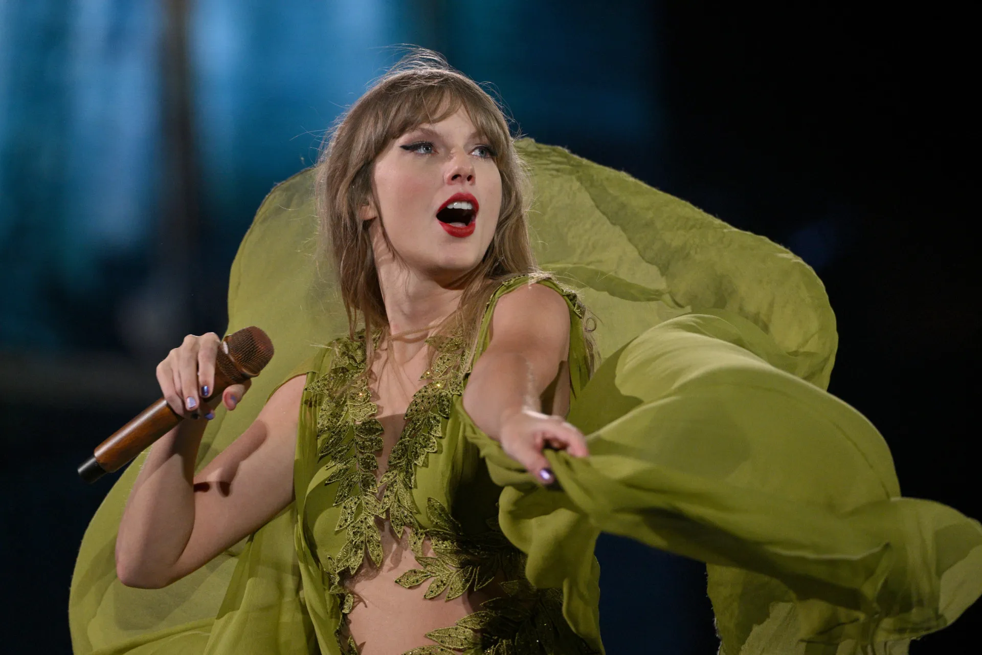 Taylor Swift tocando violão no palco, uma imagem que remete ao início de sua carreira.