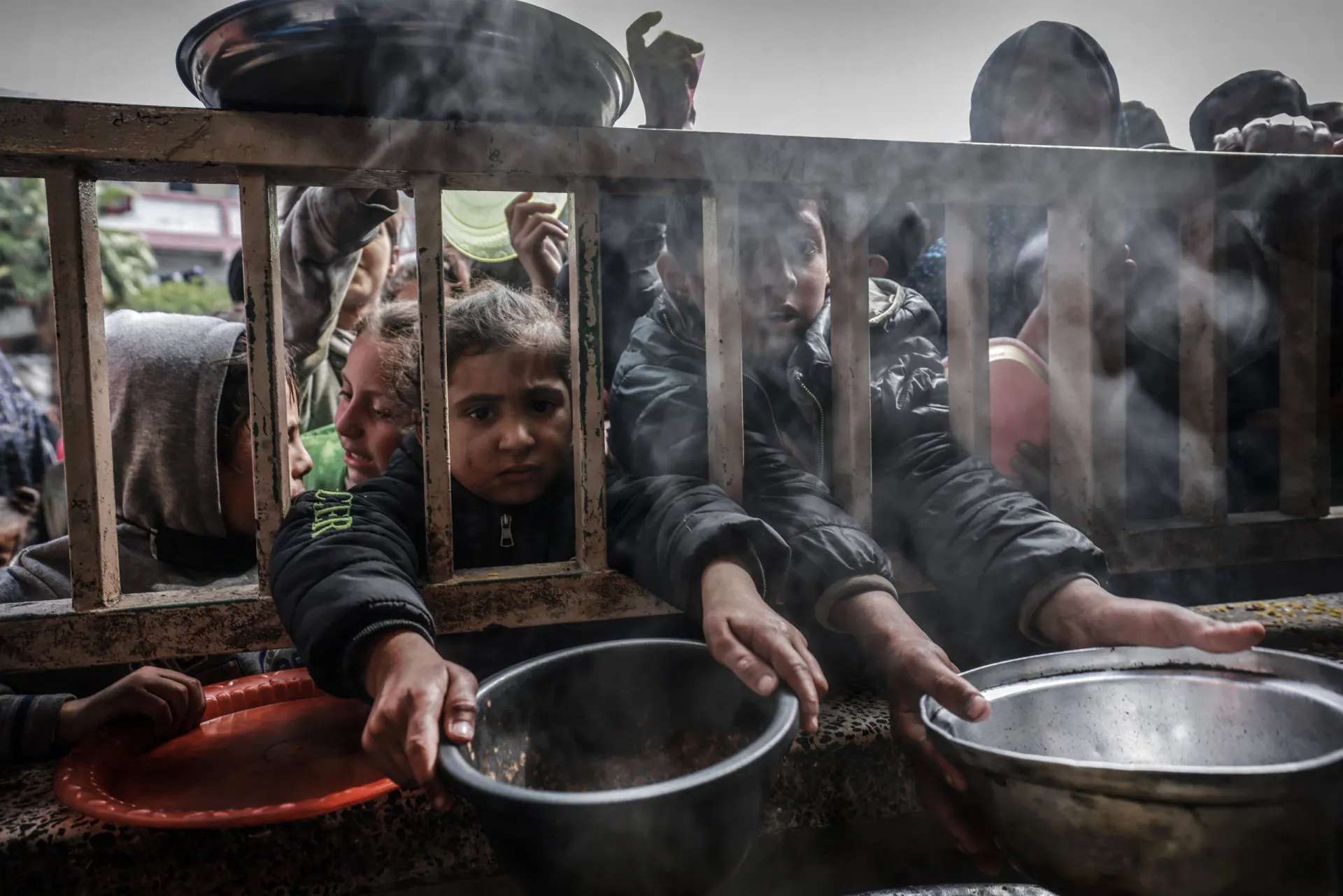 Criança desnutrida recebendo uma tigela de comida de um trabalhador humanitário.