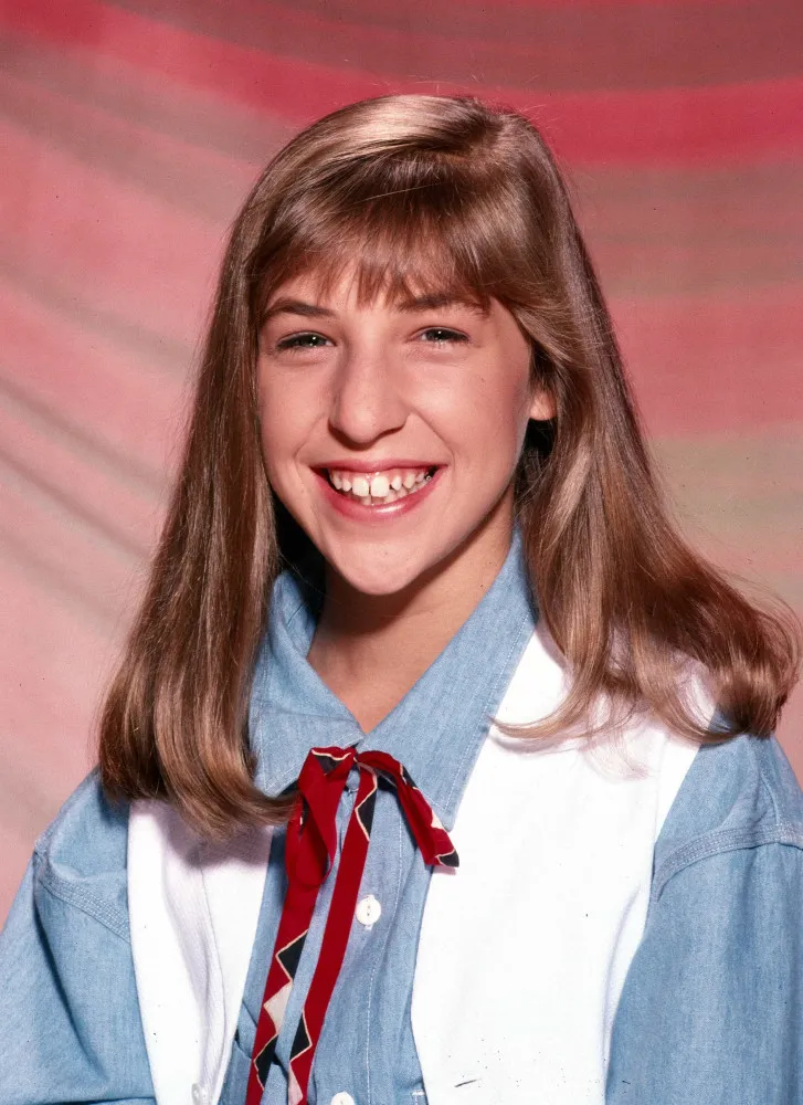 A jovem Mayim Bialik como a personagem Blossom, com seu chapéu característico dos anos 90.