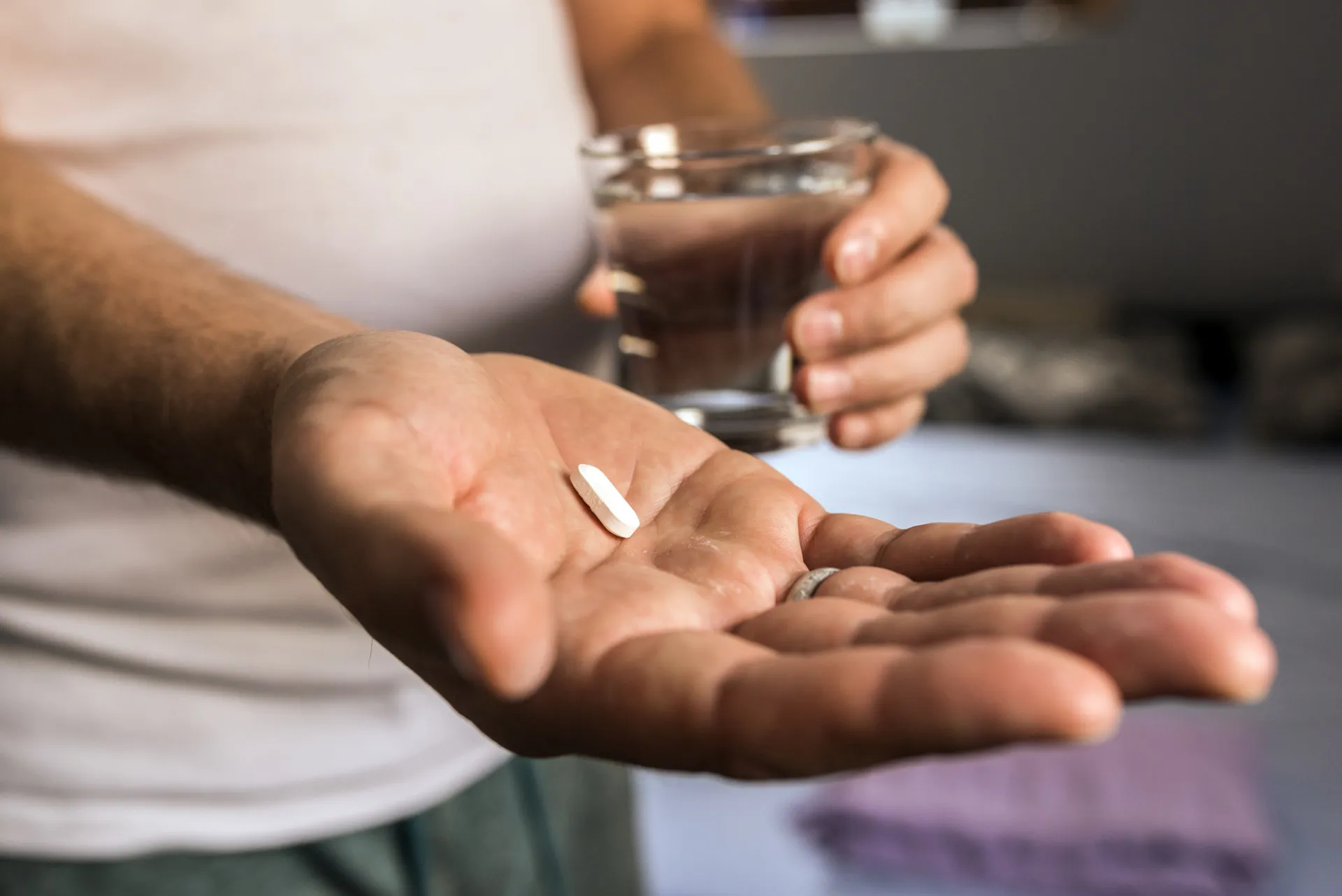 Duas mãos trocando uma pílula, simbolizando o compartilhamento de medicamentos.