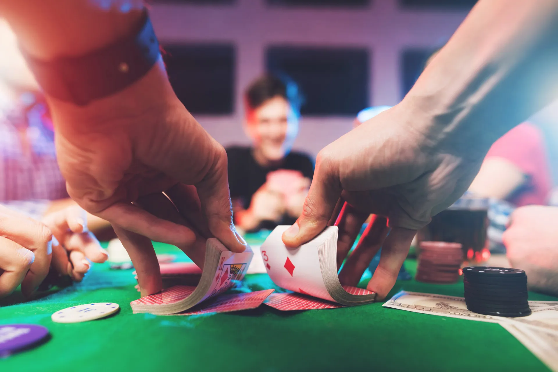 Um grupo de amigos jogando cartas e apostando fichas em uma mesa.