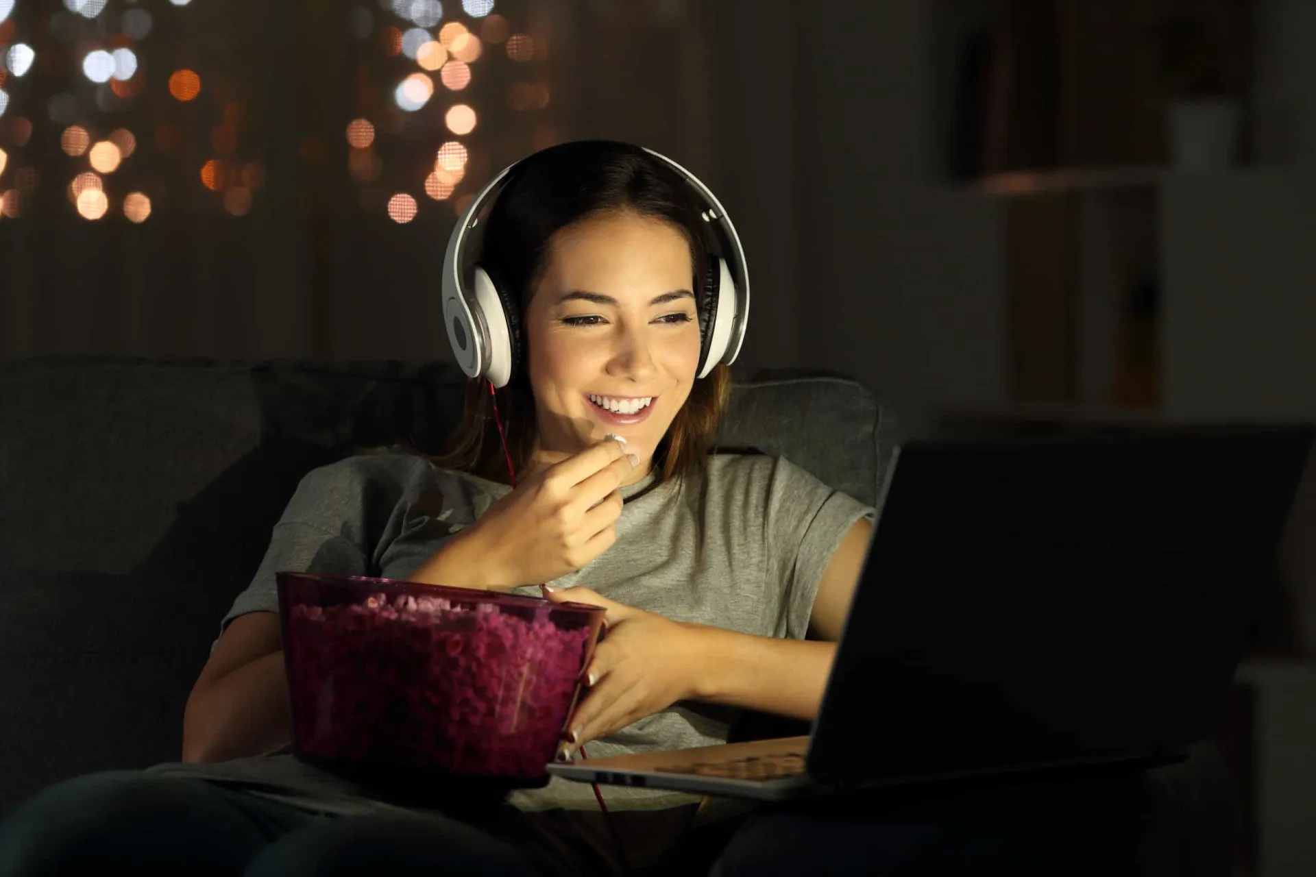 Uma pessoa assistindo a um filme em um notebook com um símbolo de pirataria (caveira e ossos cruzados) na tela.