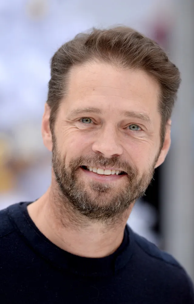 Jason Priestley hoje, com barba e um visual mais casual, demonstrando sua paixão pelo automobilismo.
