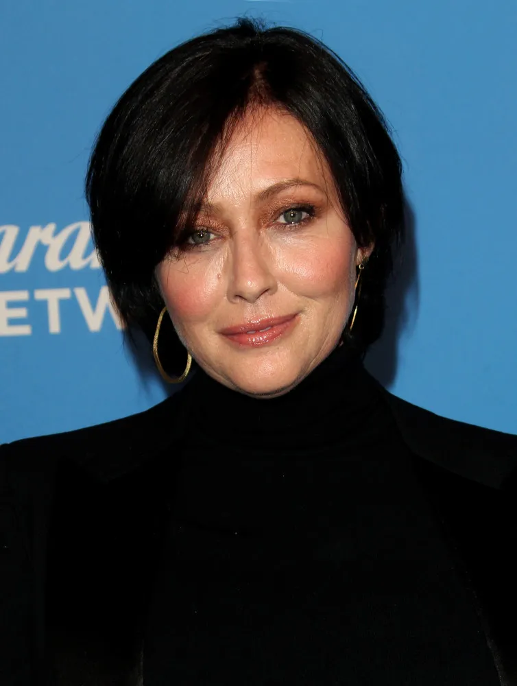 Shannen Doherty sorrindo, em uma foto que captura sua força e resiliência durante sua luta contra o câncer.