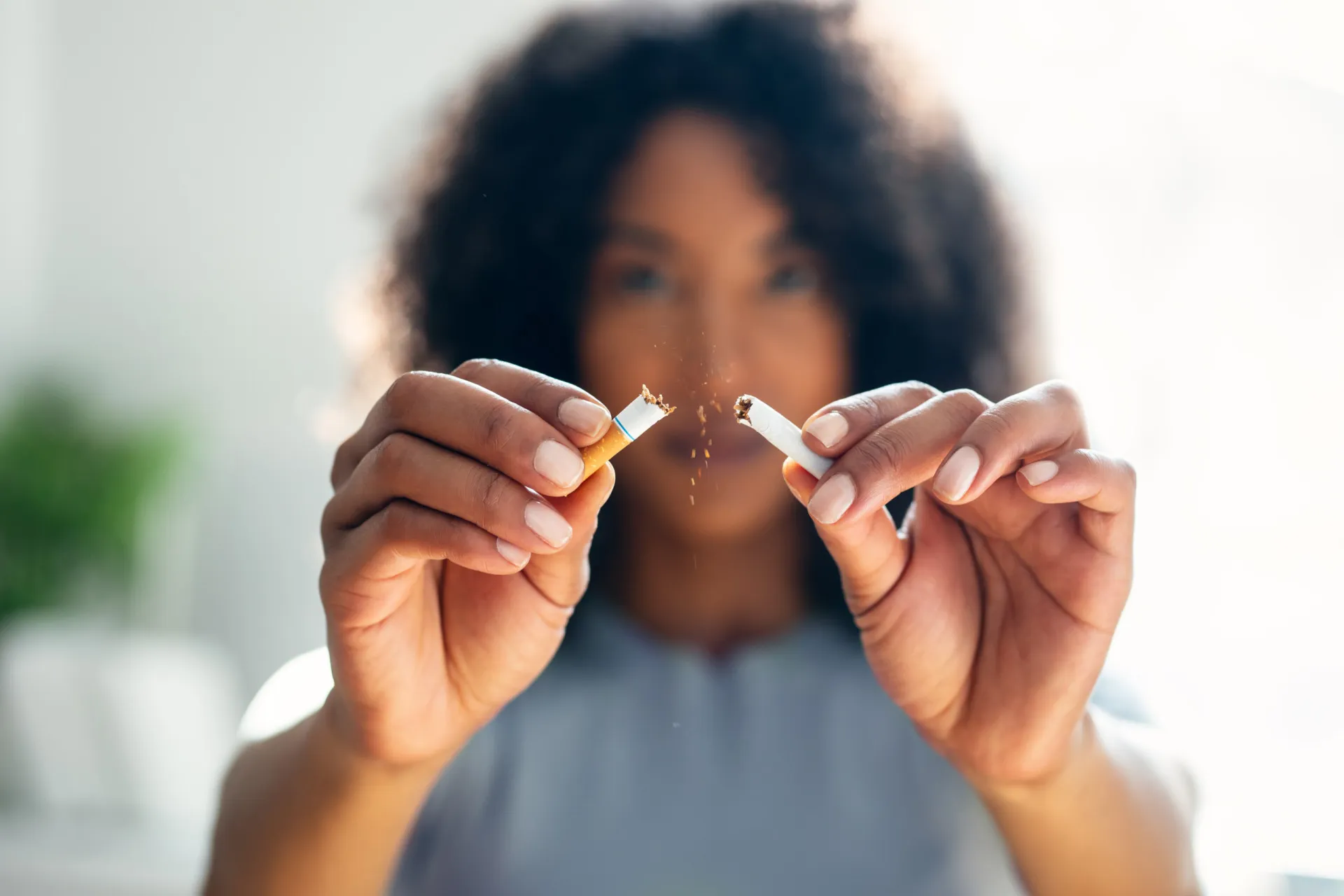 Pessoa quebrando um cigarro ao meio, simbolizando a decisão de parar de fumar.