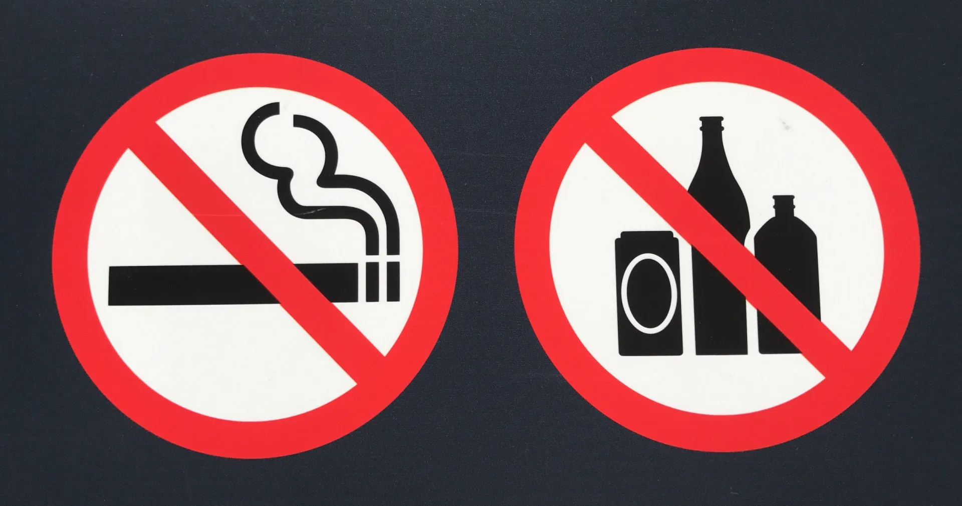 Copo de bebida alcoólica ao lado de um cigarro aceso em um cinzeiro.