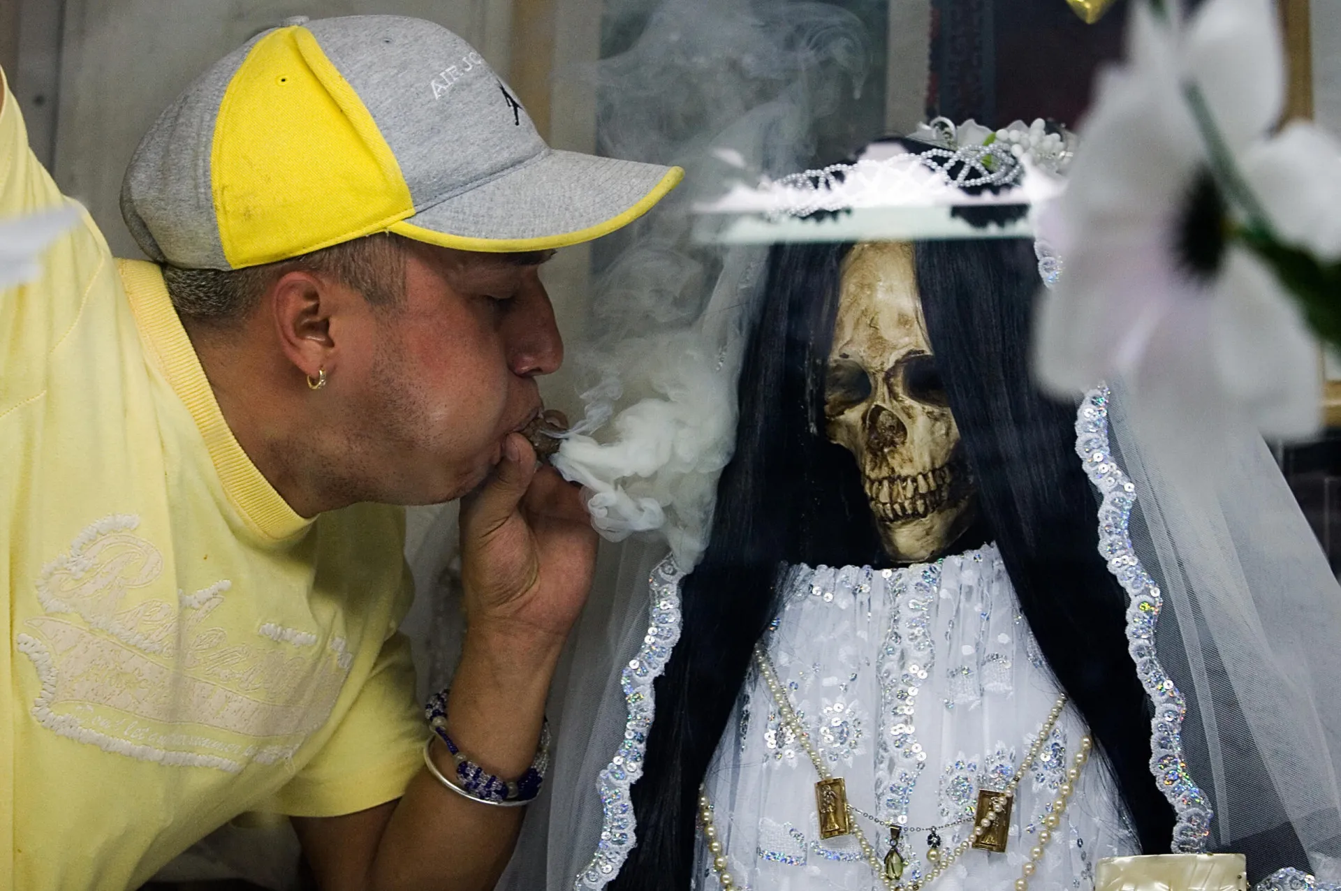 Um altar dedicado à Santa Muerte, com estátuas, velas, flores e oferendas.