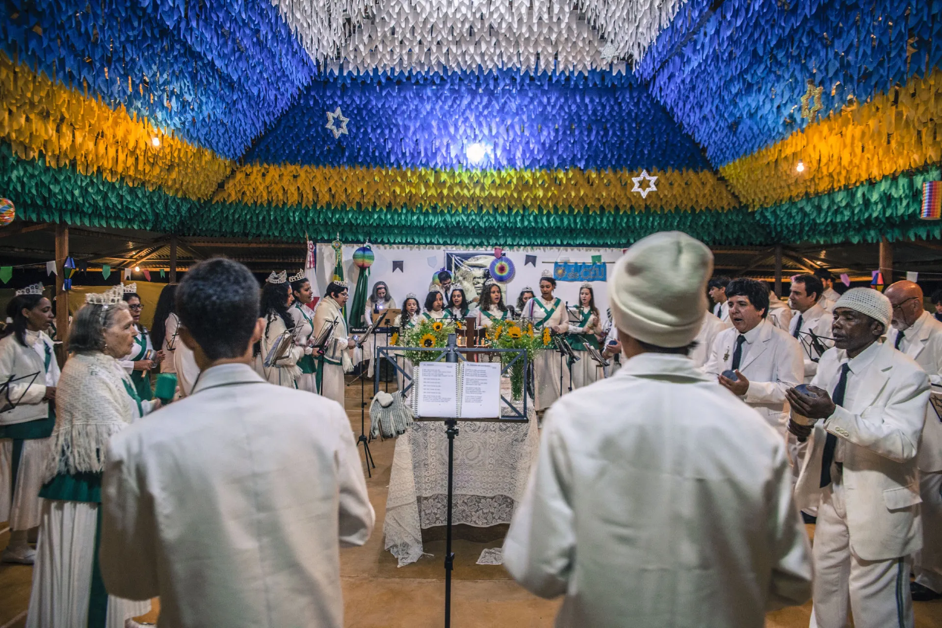 Membros do Santo Daime reunidos em um ritual, vestidos de branco em um ambiente natural.