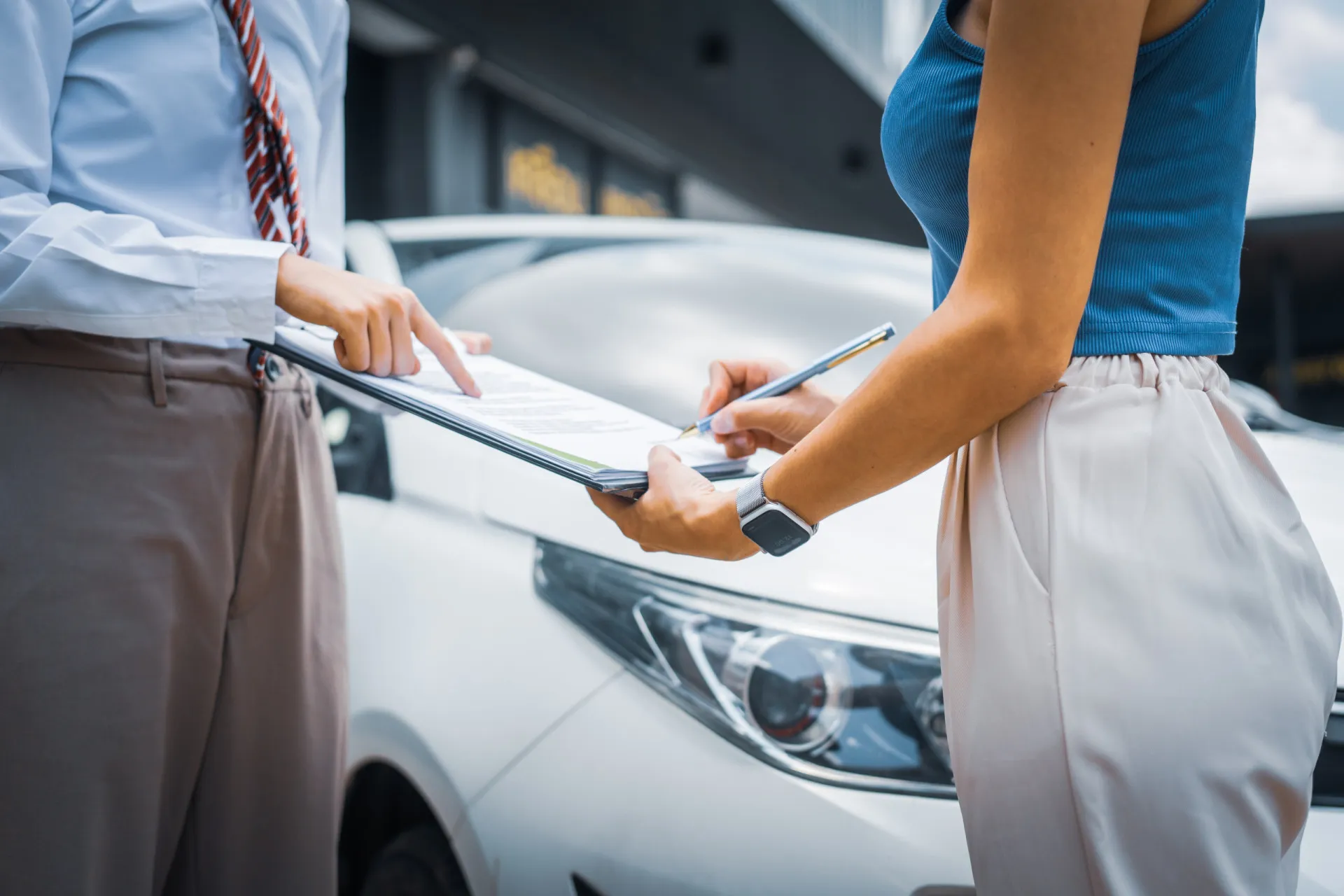 Agente de seguros analisando uma apólice com a imagem de um carro elétrico ao fundo.