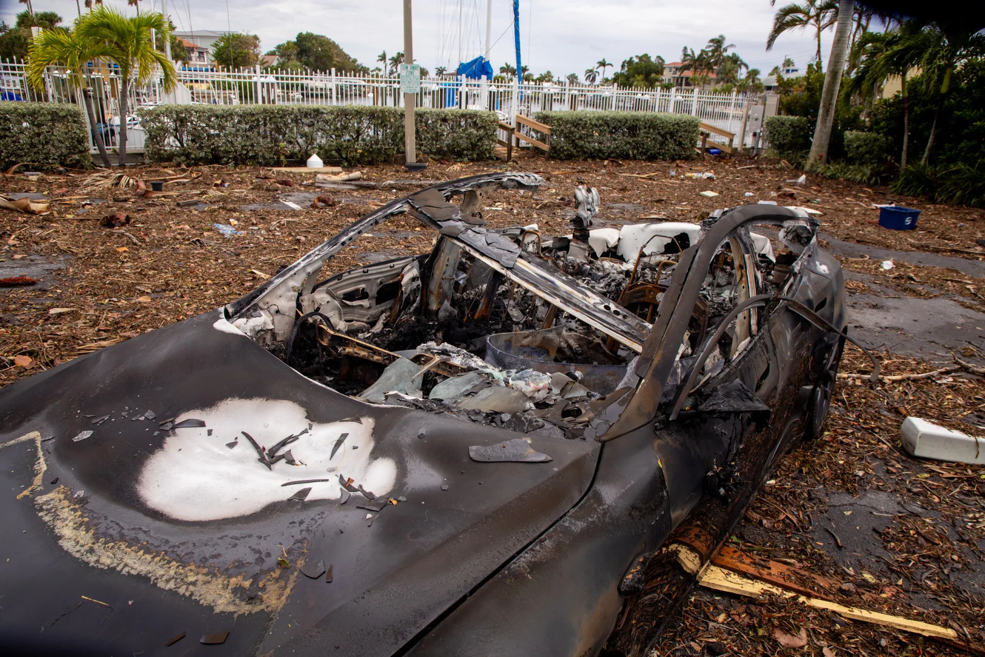 Carro elétrico parcialmente submerso em uma rua inundada por água do mar após um furacão.
