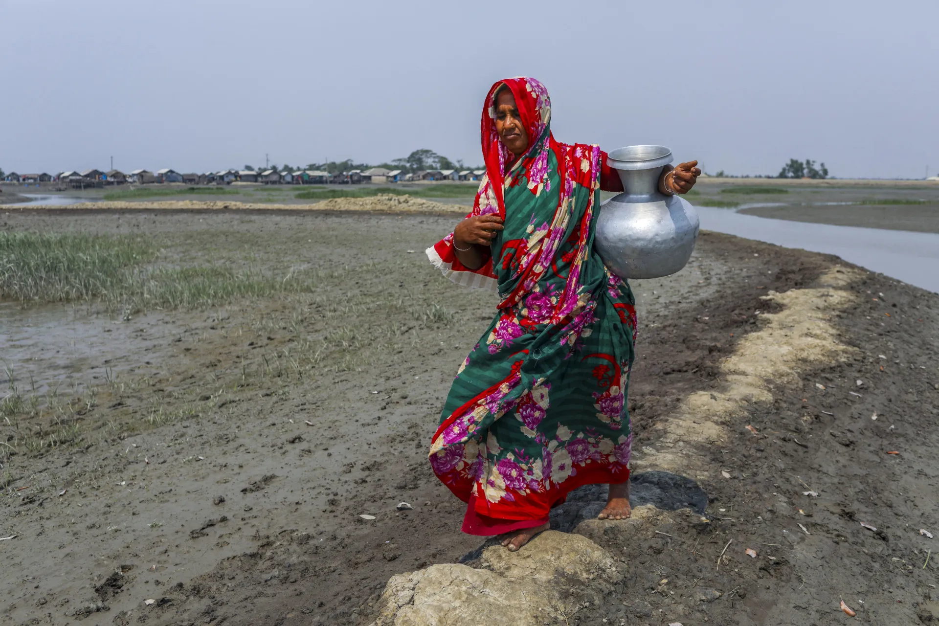 Área inundada em Bangladesh, com casas e pessoas ilhadas.
