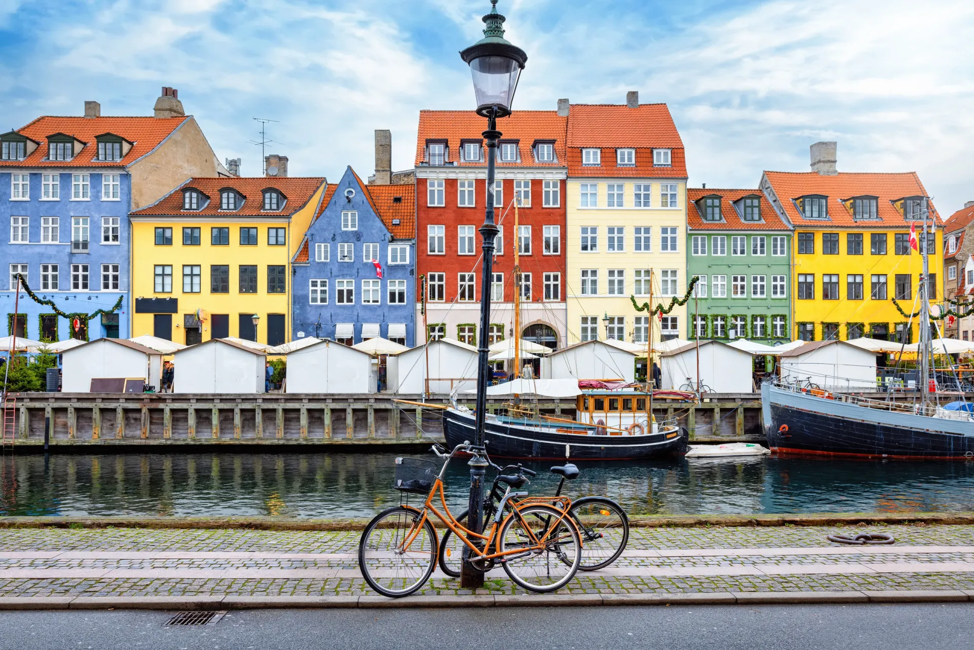 Casas coloridas à beira do canal em Nyhavn, Copenhague, com barcos ancorados.