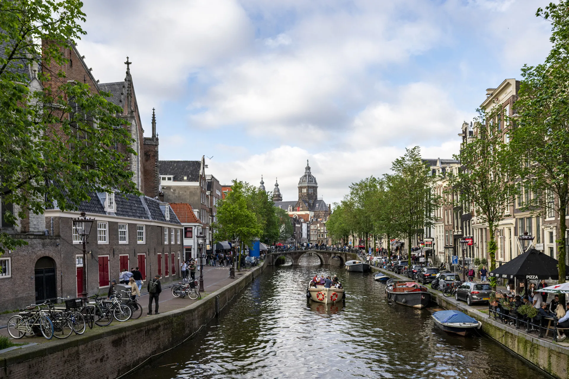 Canais e casas típicas de Amsterdã, com bicicletas estacionadas na ponte.