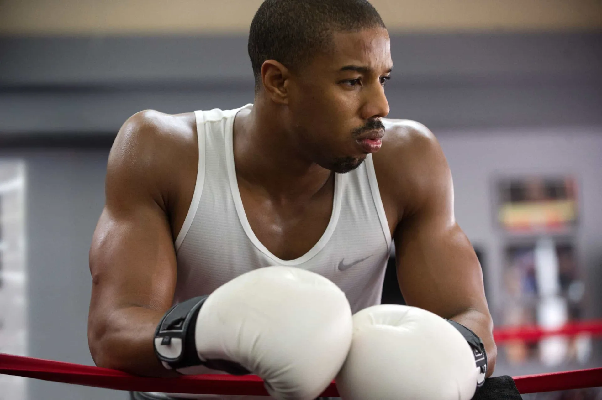 Michael B. Jordan no ringue de boxe como Adonis Creed, com um físico de lutador extremamente definido.