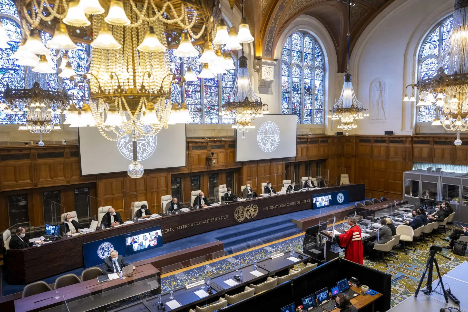 Bandeiras de várias nações em frente a um prédio de justiça, simbolizando a cooperação e os desafios da diplomacia.
