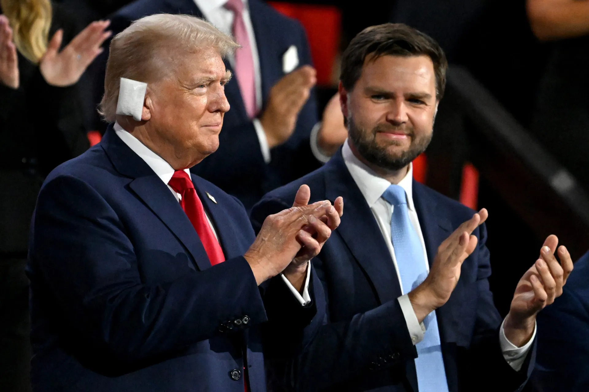Trump e Vance acenando para a multidão, projetando uma imagem de unidade e força.