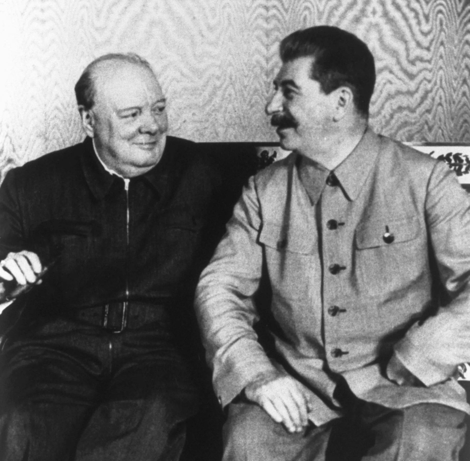Winston Churchill e Joseph Stalin sentados lado a lado em uma conferência durante a Segunda Guerra.