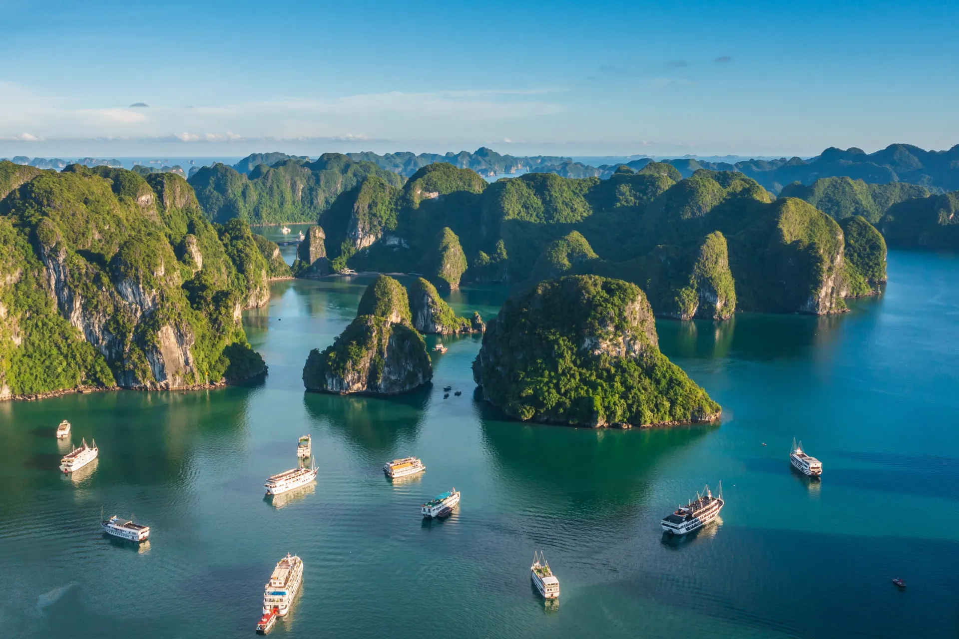 Barcos tradicionais navegando entre as formações de calcário da Baía de Halong.