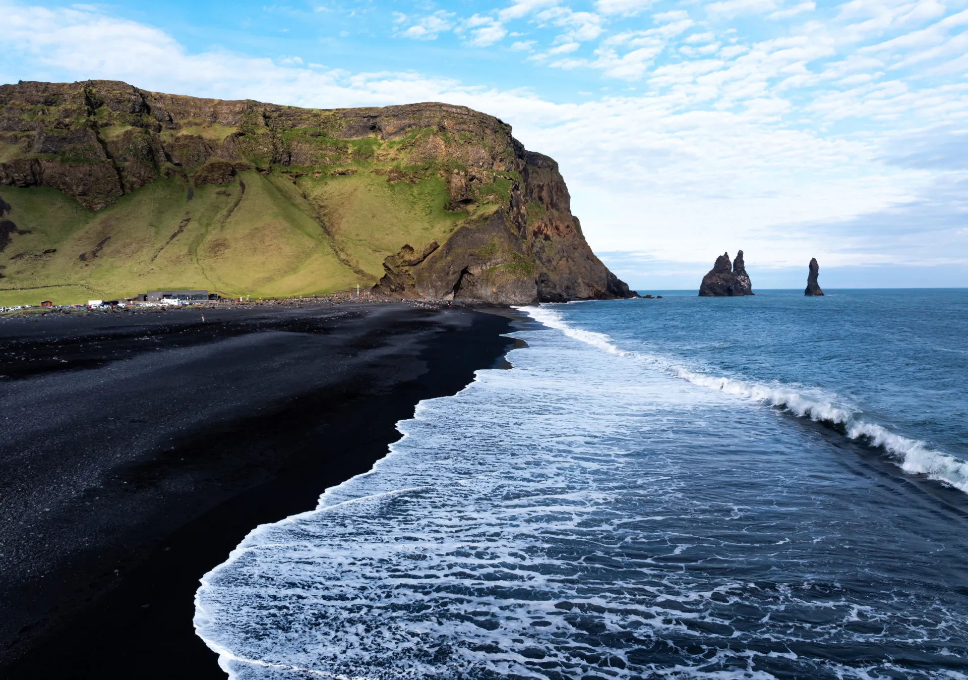 Areia preta vulcânica e colunas de basalto na dramática Praia de Reynisfjara, na Islândia.
